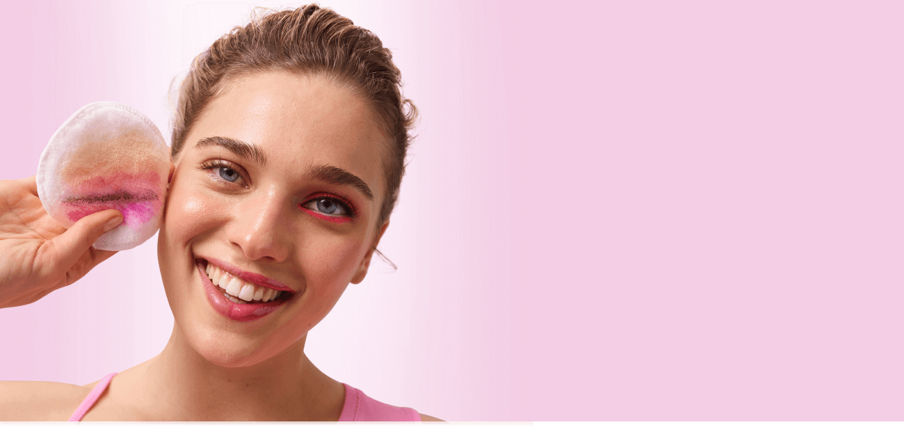 Uśmiechnięta modelka z wrażliwą skórą zmywa makijaż płynem micelarnym 3w1 i pokazuje pozostałości makijażu z oka, na waciku